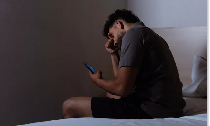 Person looking at a phone while sitting on a bed
