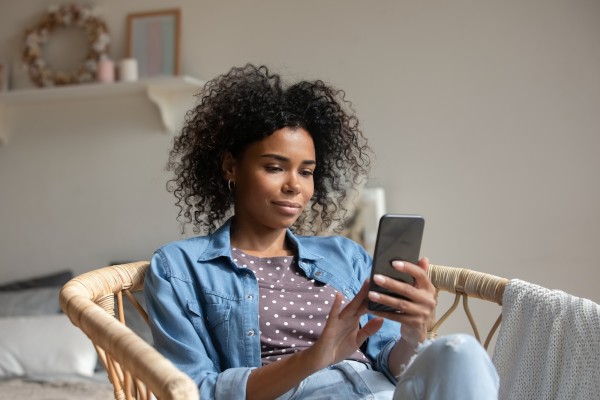 Black woman sitting down in a chair and looking at her phone