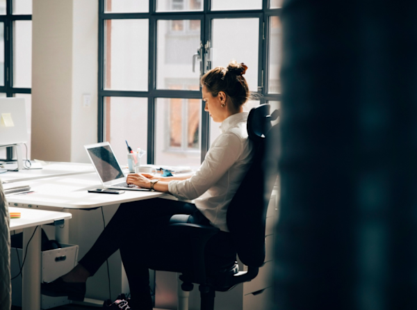 A woman working in an office by windows.