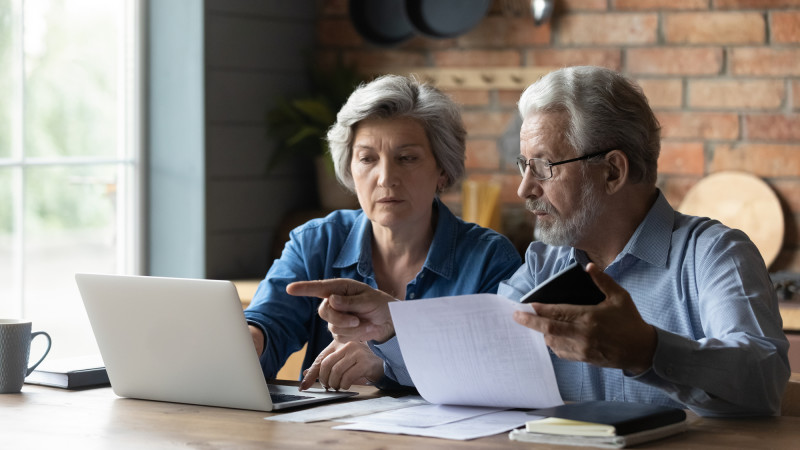 Older couple sitting down and looking at a laptop