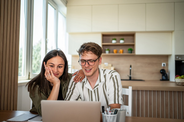 Man and woman sitting at a table and looking at a laptop