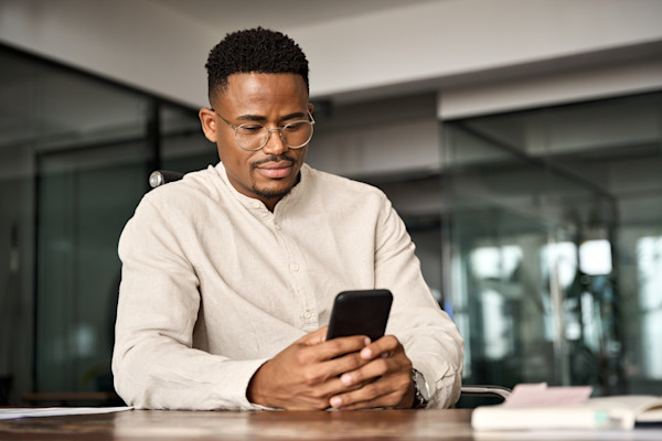 Black man wearing glasses looking at his phone