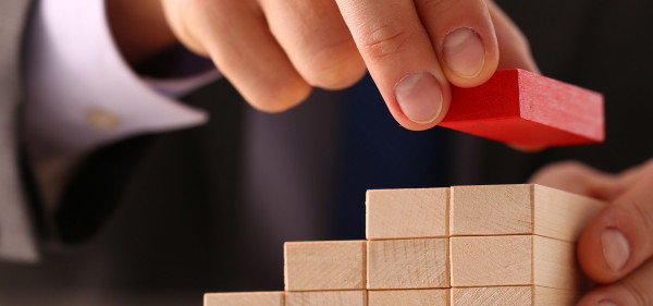 Close up of hand stacking wooden blocks.  Red block. Jpg.
