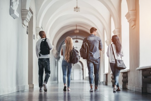 Four college students walking away down a hall