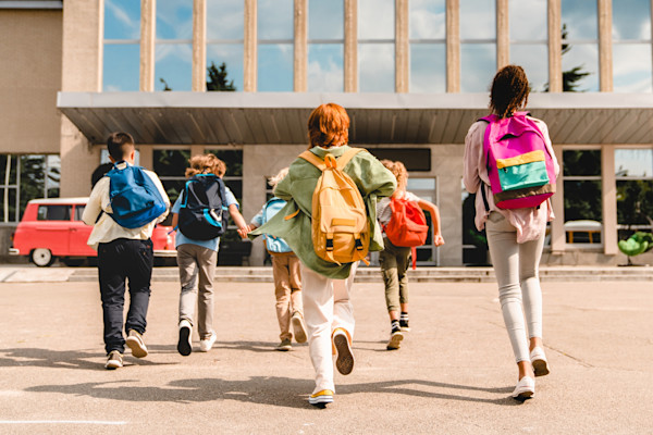 Kids running into school with backpacks on