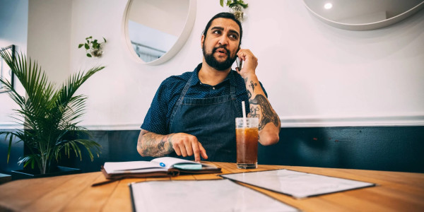 A man in a restaurant with a cup of coffee makes a call on his cell phone