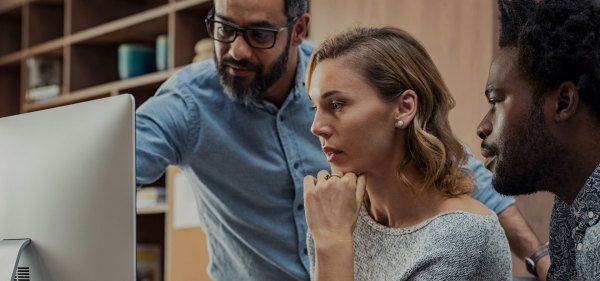 Two men and a woman look at computer screen