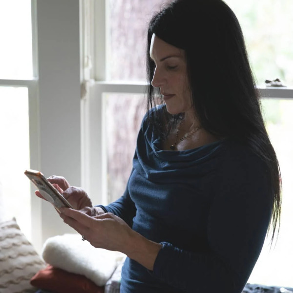 Woman on mobile device wearing blue shirt and wedding ring. JPG
