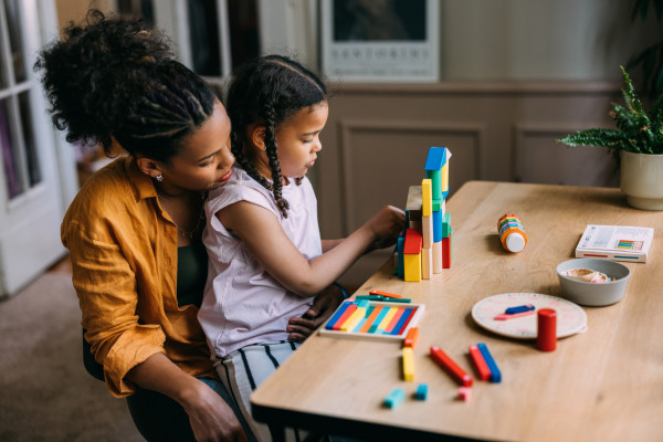 Mom and daughter sitting a table and playing 