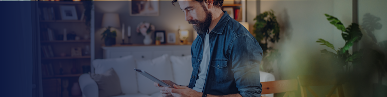 A man standing in his living room looking at a mobile device (gradient)
