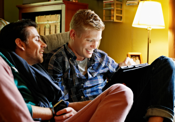 Two men sitting on the couch with their electronic devices. JPG