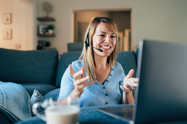 A female customer service rep works from home and smiles with a headset on