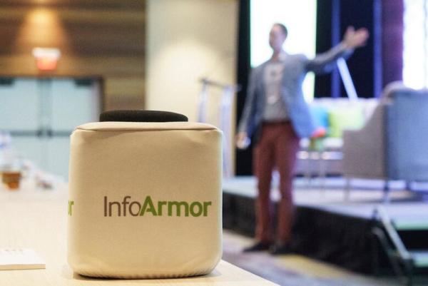 New InfoArmor logo on tossable mic with Ammon Curtis giving a partner summit talk in the background