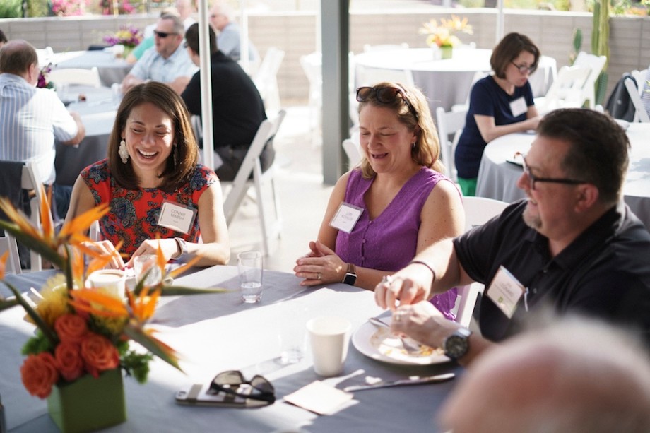 Partner summit guests laugh over breakfast outside