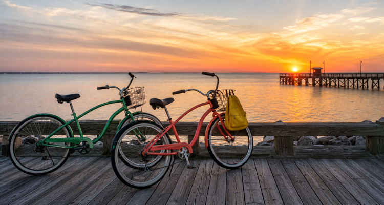 two-bicycles-on-seaside-boardwalk-at-sunset-750x400