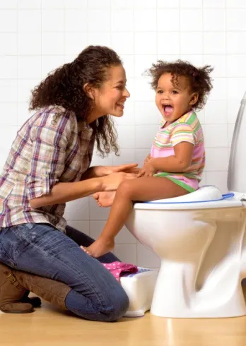 Mom smiling at child sitting on toilet potty training