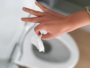 Person dropping a piece of Charmin toilet paper into the toilet