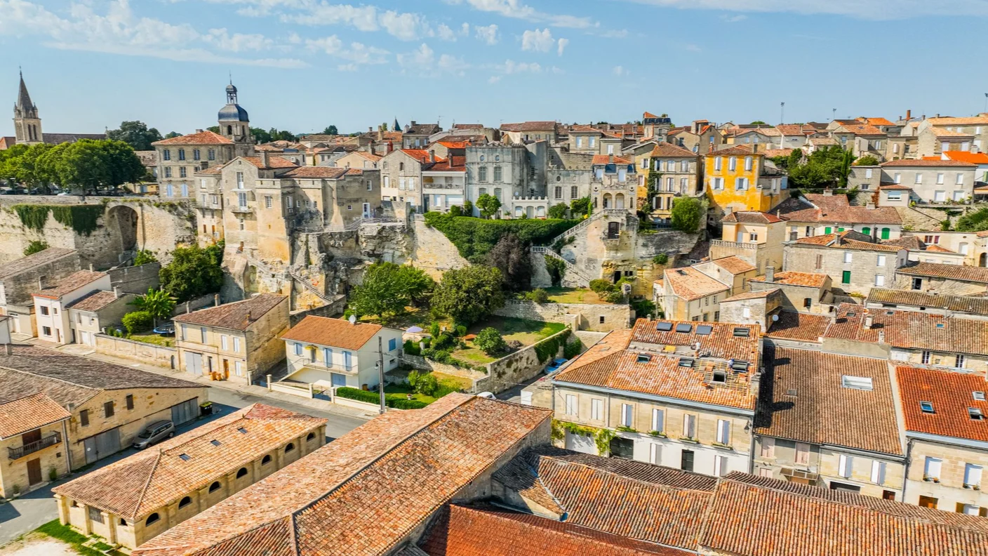 Aerial view of Bourg with historic stone buildings, terracotta rooftops and a cliffside overlooking the town.