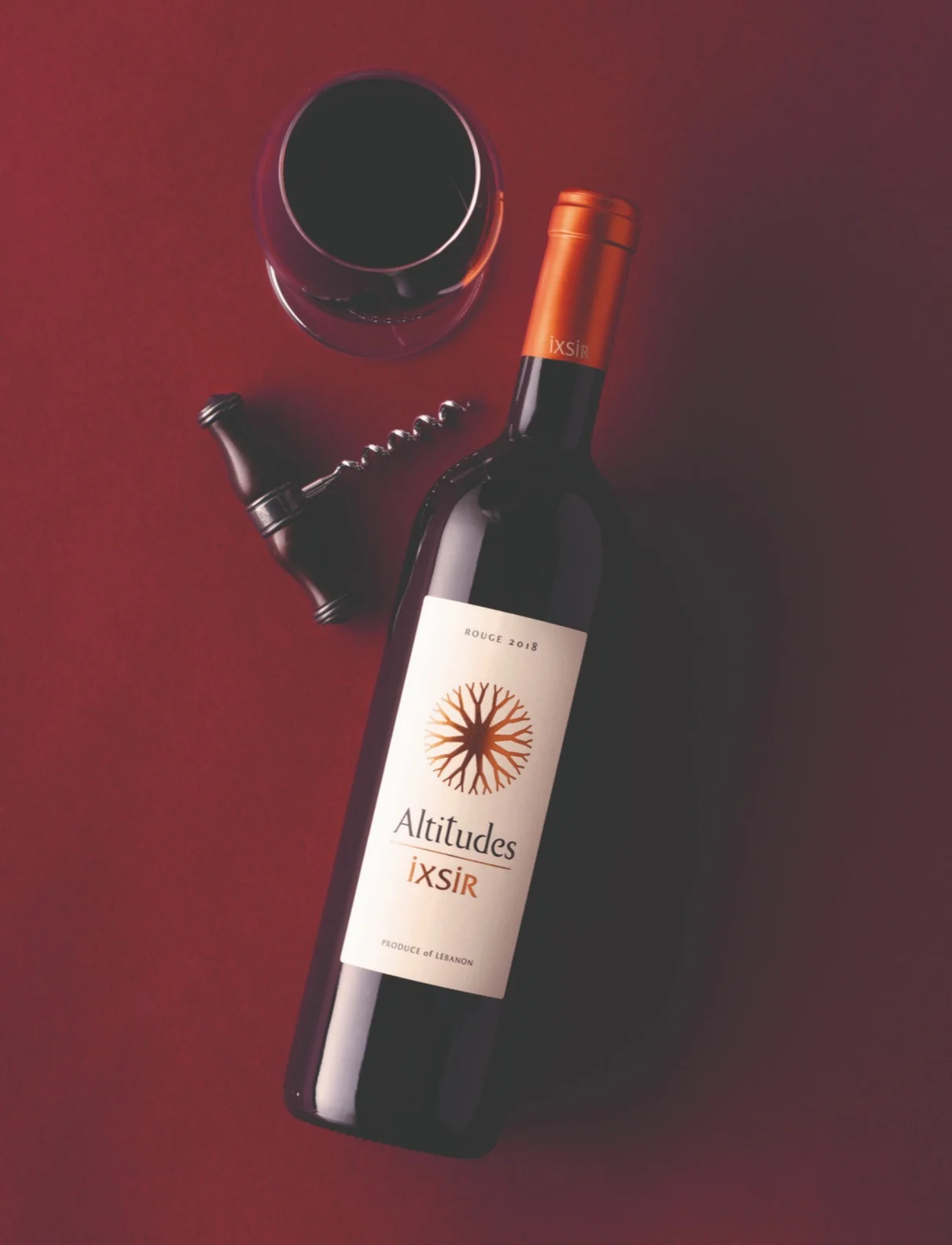 Altitudes Ixsir red wine bottle with a glass of red wine and corkscrew.