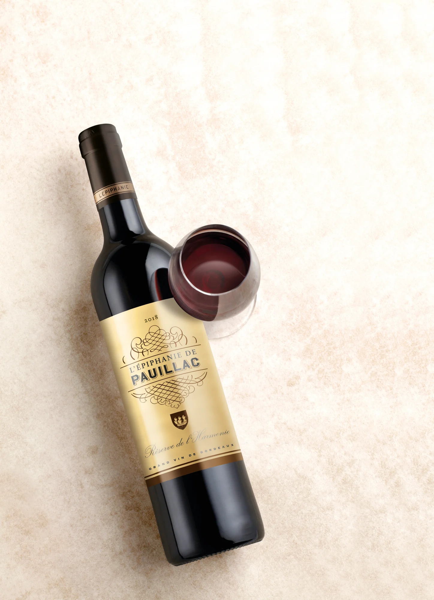Bottle of L'Épiphanie de Pauillac red wine with a glass of red wine and corkscrew.