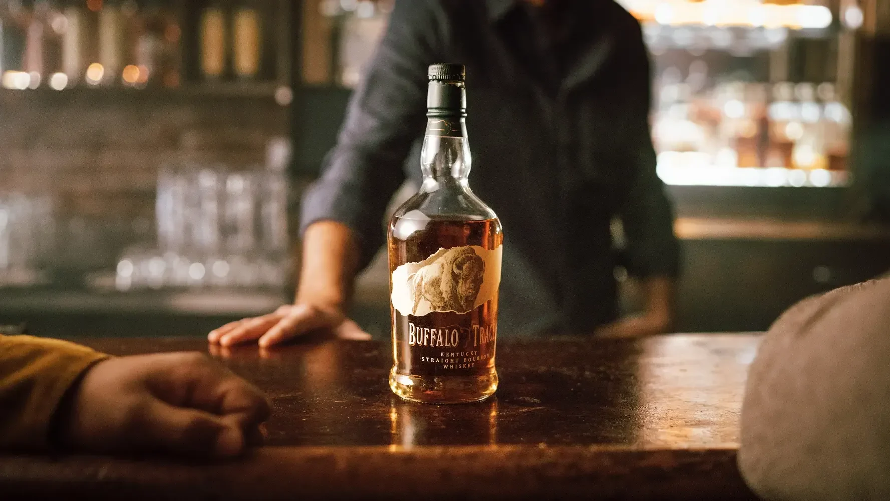Buffalo Trace bourbon on a wooden bar waiting to be poured.