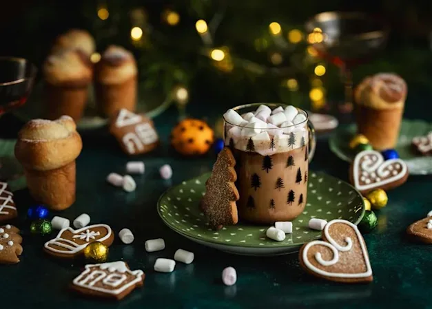 Red Wine Hot Chocolate Christmas Cocktail, in a clear mug which sits on a green plate, with a gingerbread heart biscuit next to it.