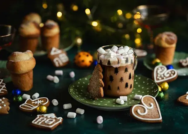 Red Wine Hot Chocolate Christmas Cocktail, in a clear mug which sits on a green plate, with a gingerbread heart biscuit next to it.