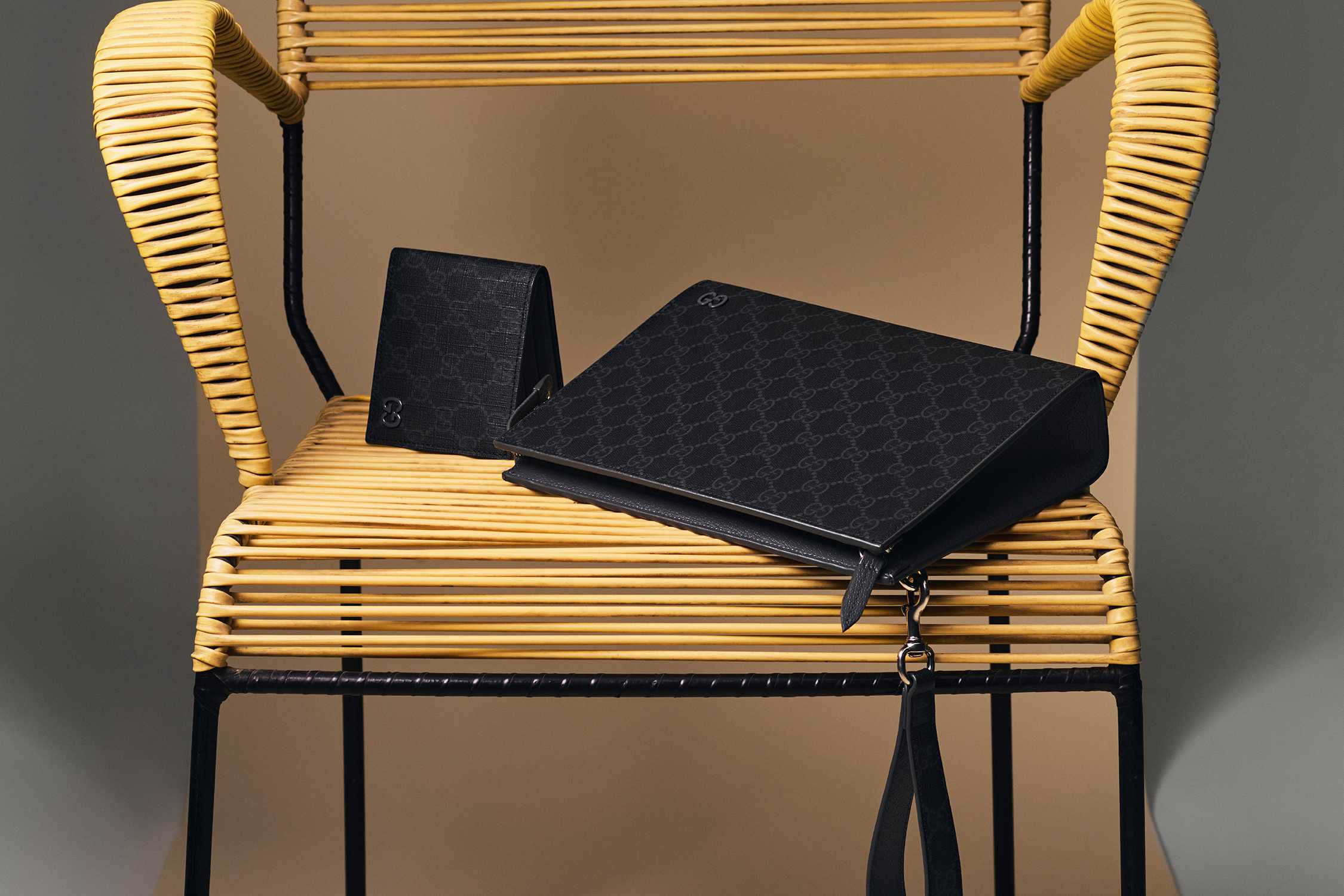 Black Gucci accessories on rattan chair.