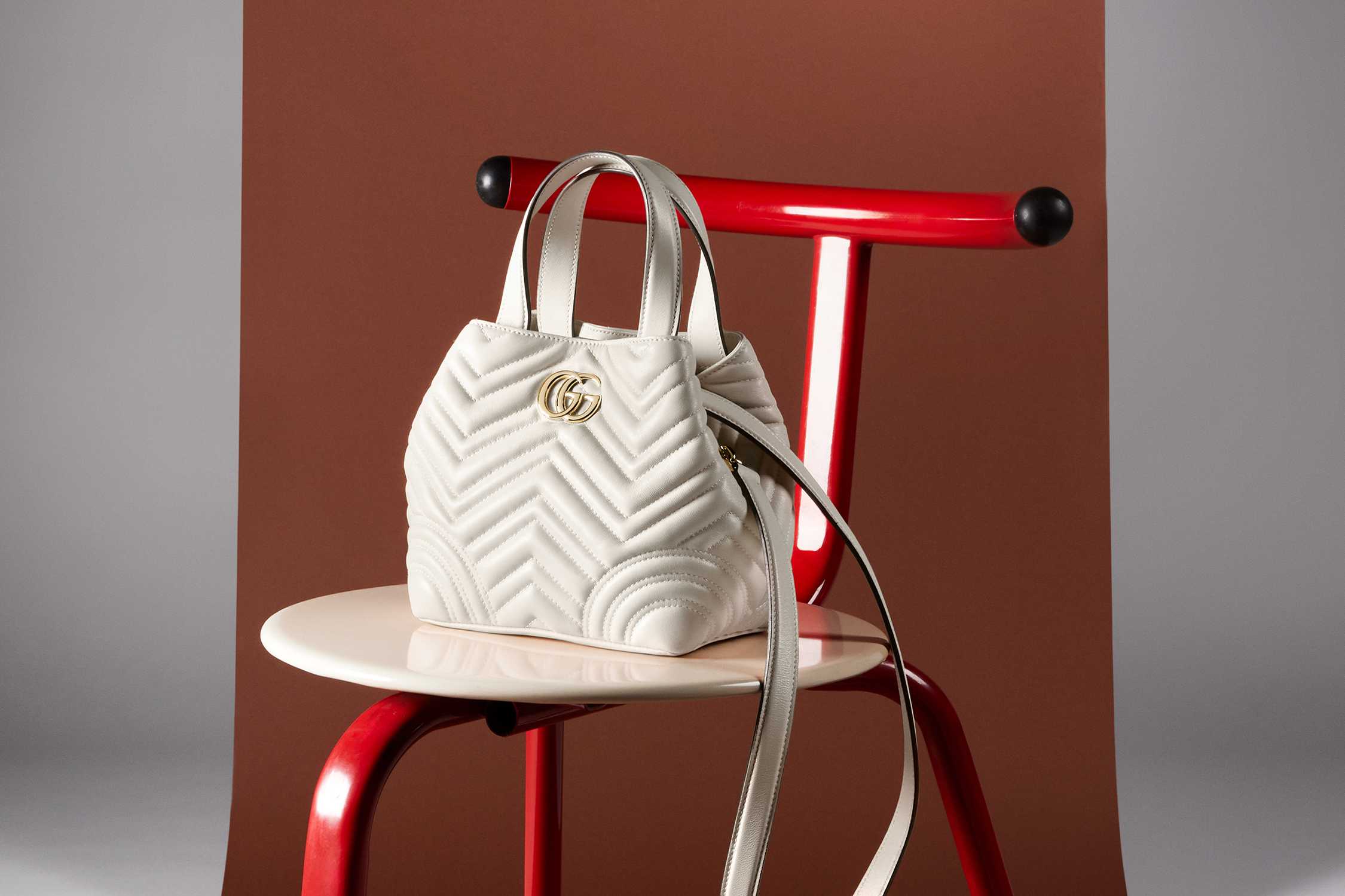 White Gucci handbag on red chair.