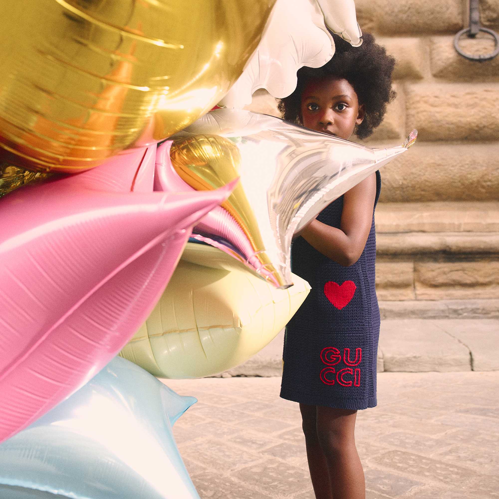 Child wearing Gucci dress with balloons
