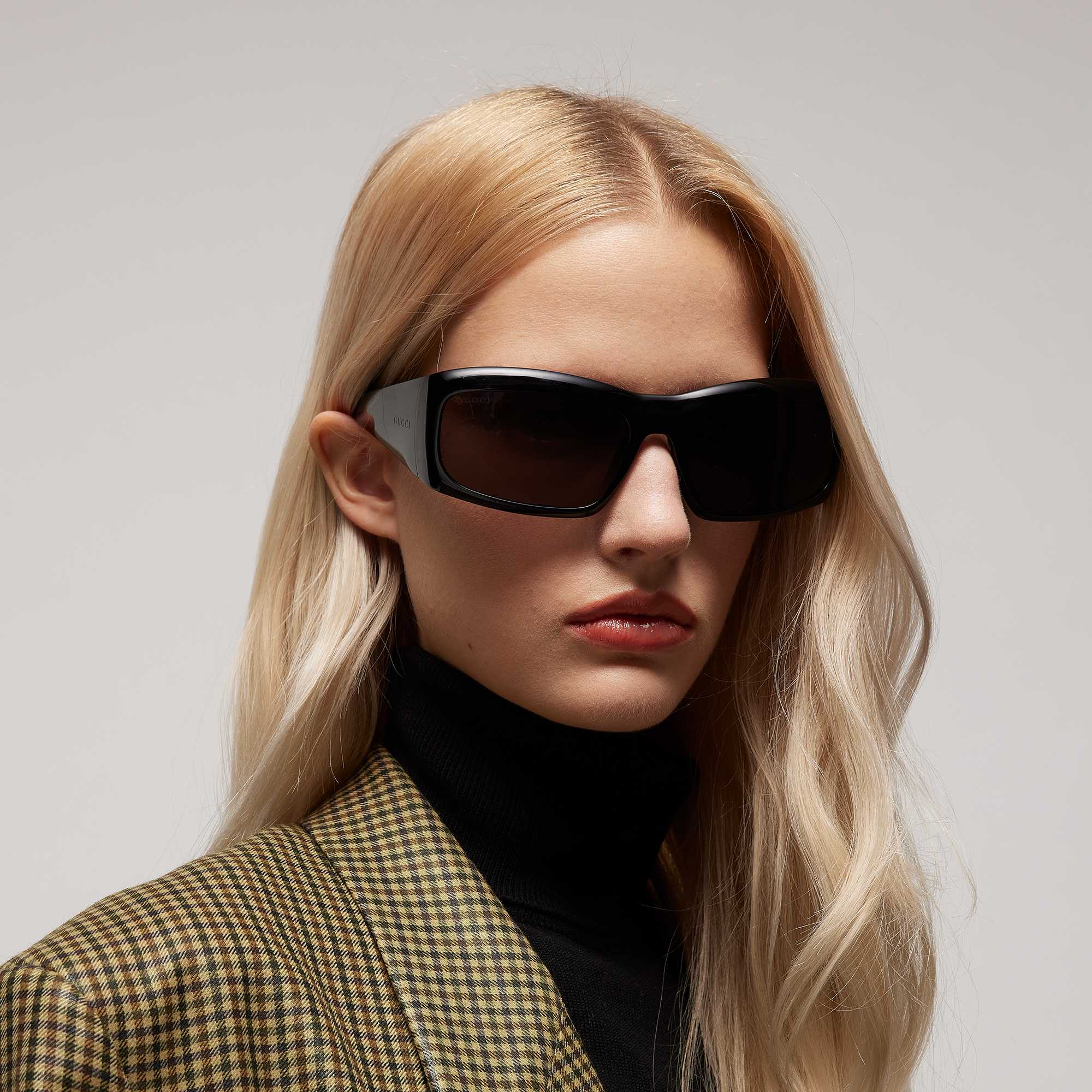 Black Gucci sunglasses, plaid blazer.