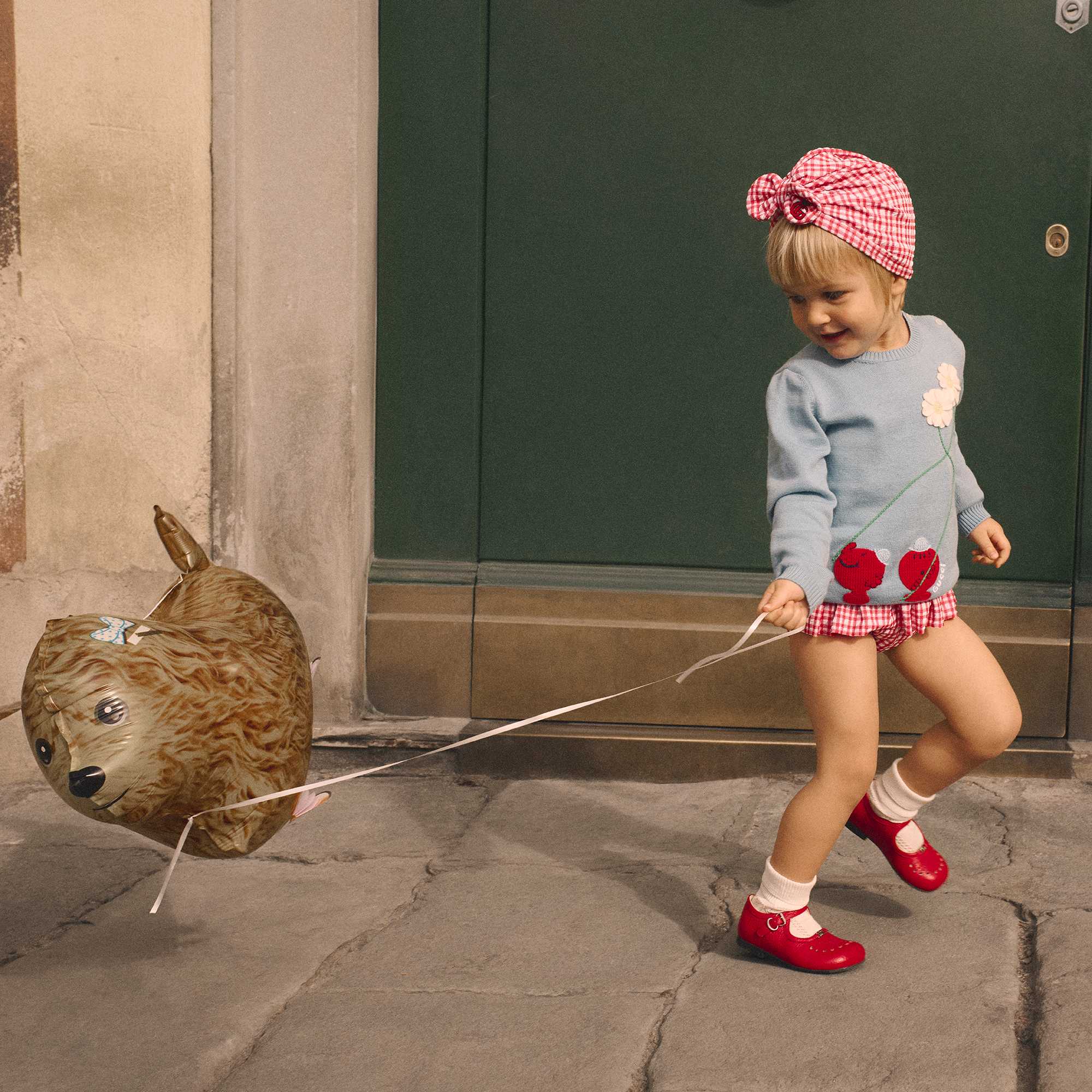 Little girl wearing Gucci playing with a balloon