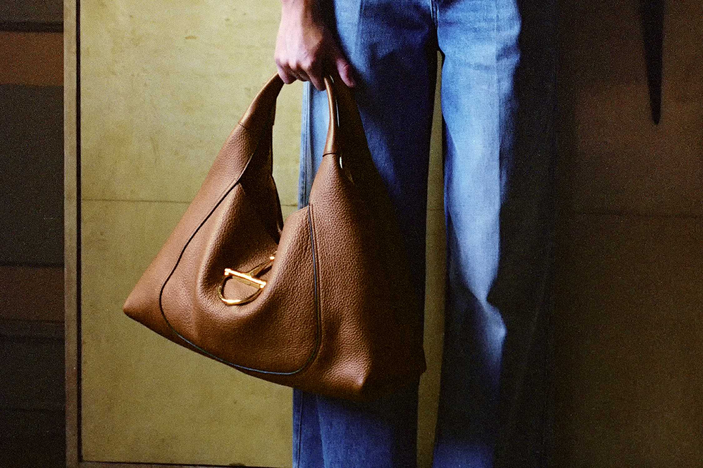 Brown Gucci leather handbag held