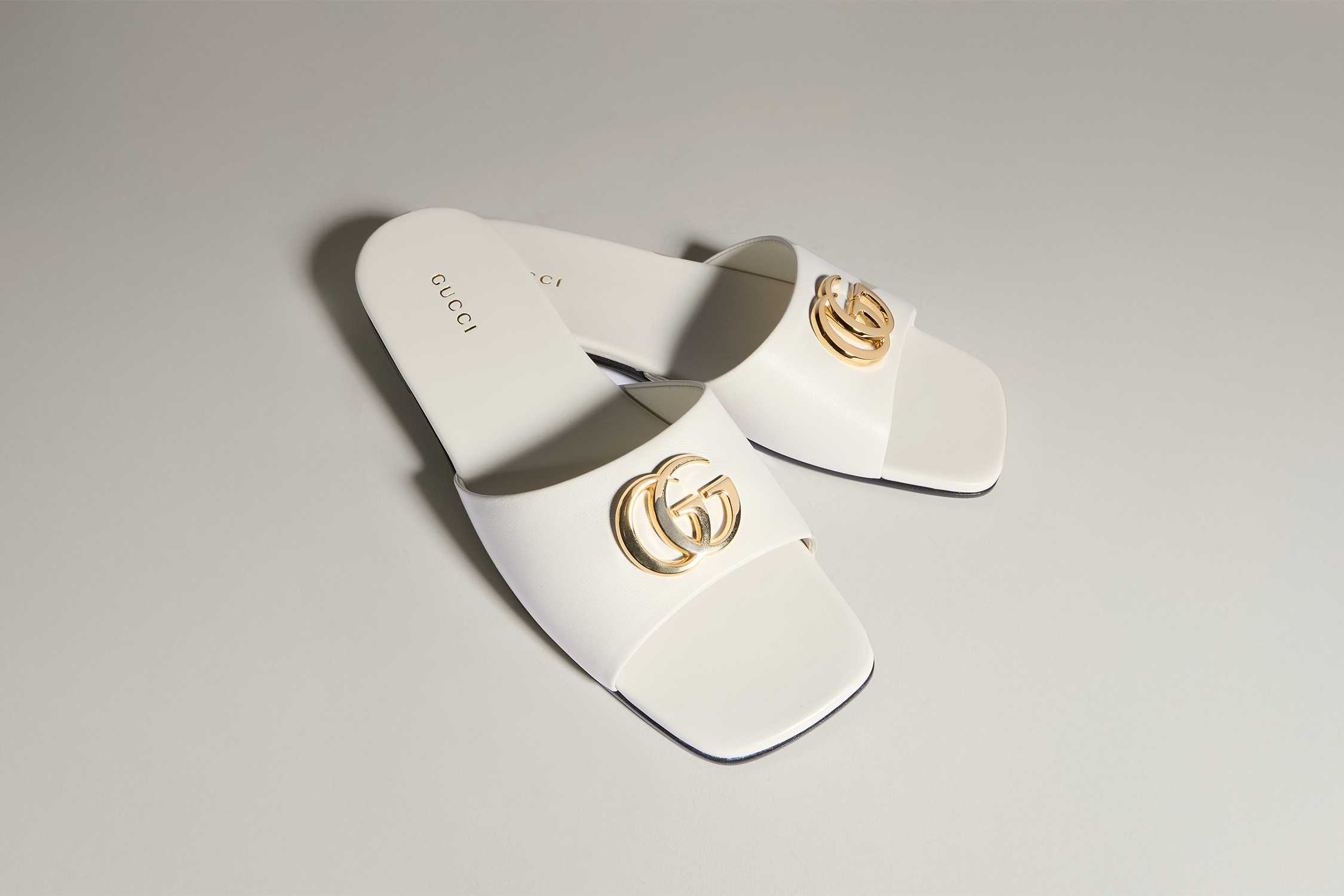 White Gucci slides with gold logo
