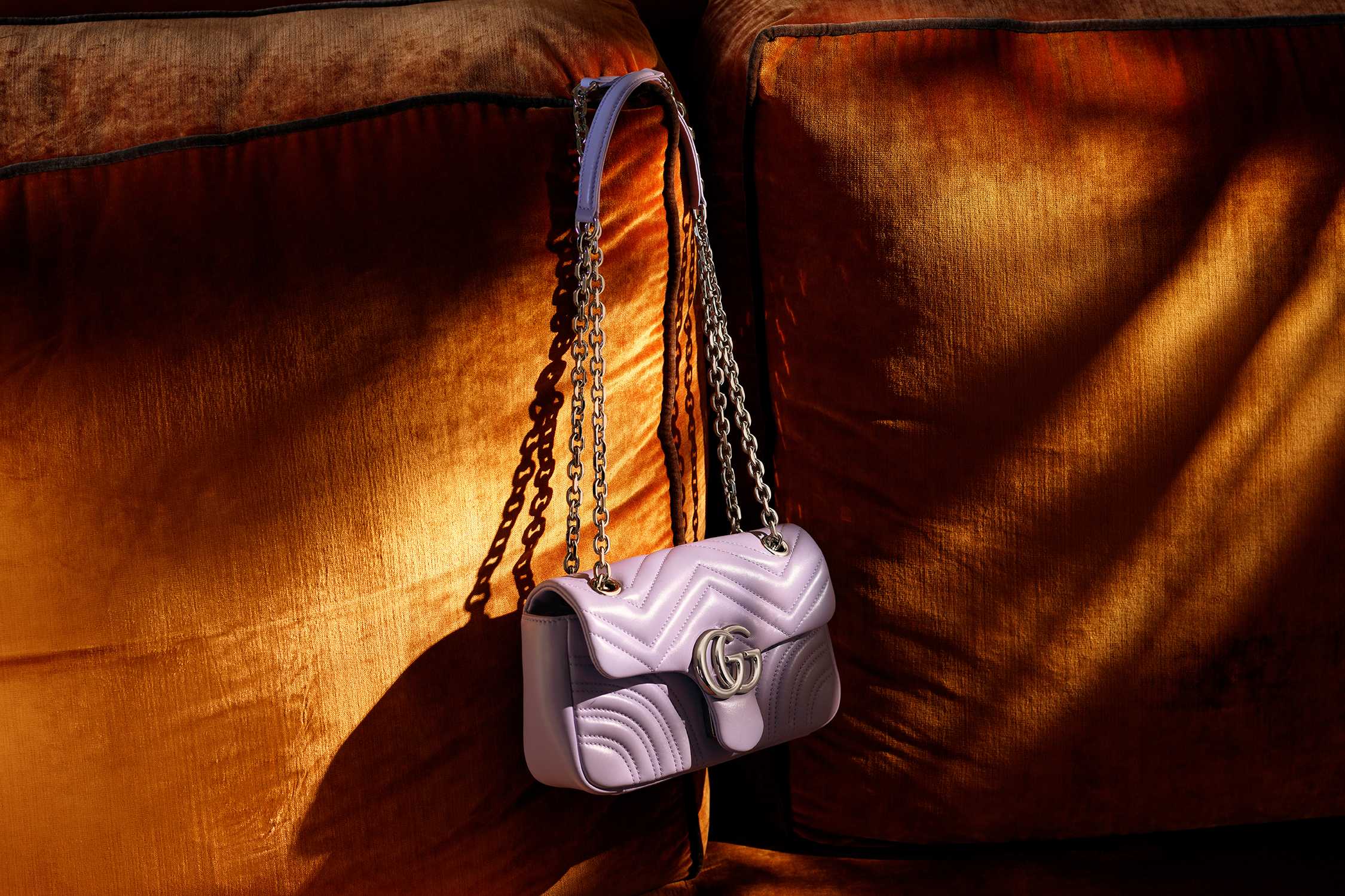 Purple leather handbag on orange sofa.