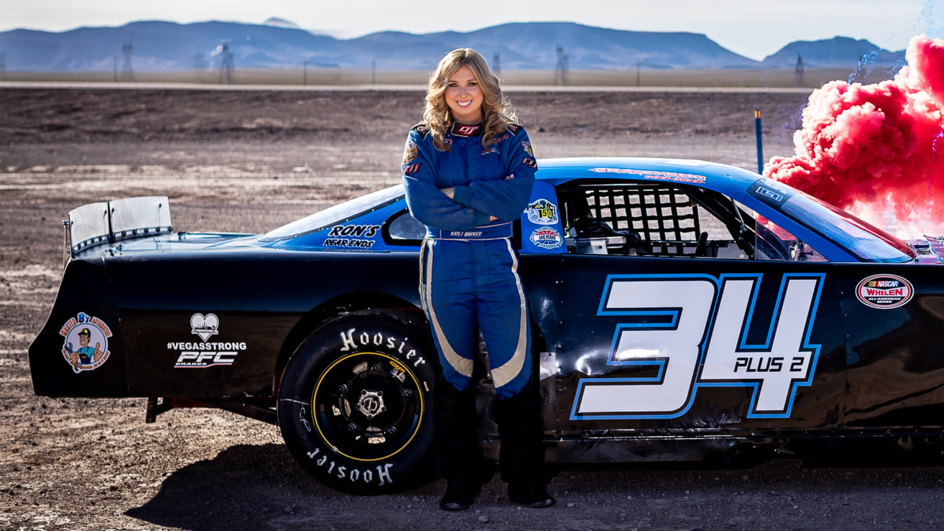 alt: Kayli Peterson stands in front of a racecar
