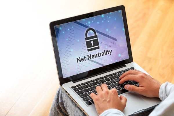 Man working on a laptop with the words ‘net neutrality’ on the screen