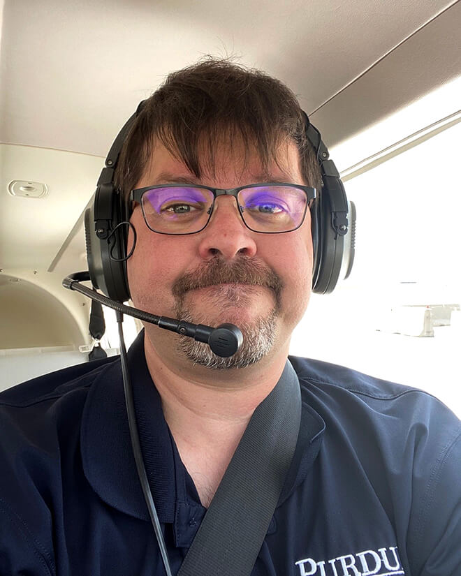 Todd Brewer poses for a selfie at work inside of a Purdue airplane.
