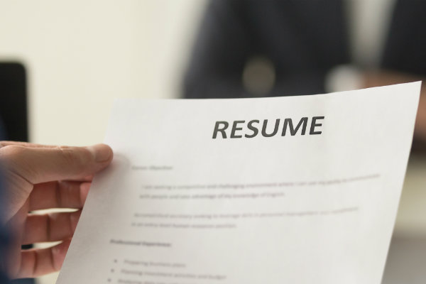 A person holds a paper resume in their hand.