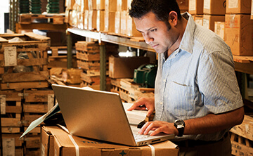 Employee working on a laptop in a warehouse