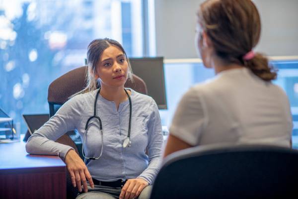 A psychiatric mental health nurse practitioner consults with a young female patient in her office.