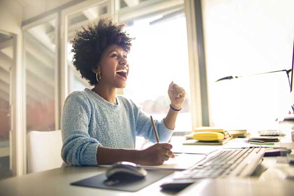 A woman smiles while sitting at a desk.