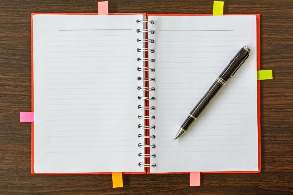 Open notebook with divider tabs and a pen.