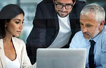 three professionals discussing something they see on a laptop