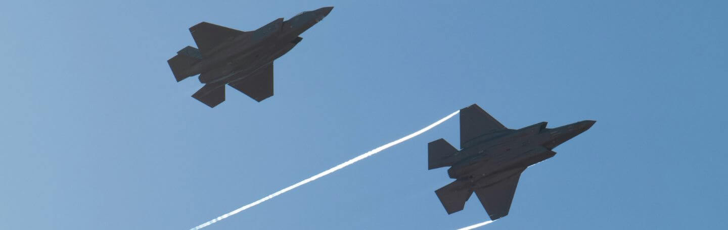 Two fighter jets flying in a bright blue sky
