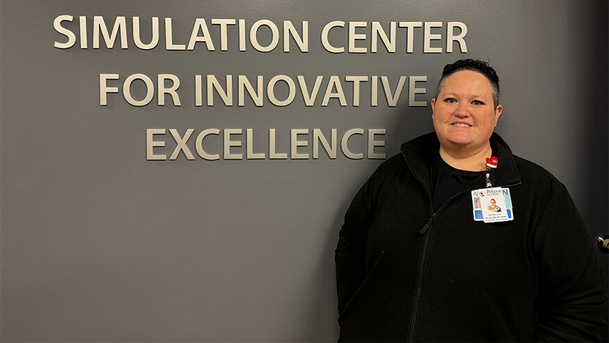 Brooke Hanner standing in front of a sign that says "Simulation Center for Innovative Excellence"
