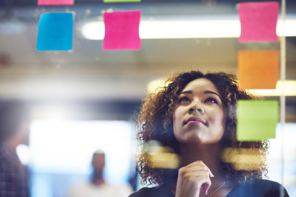 A woman ponders marketing ideas at a glass partition.