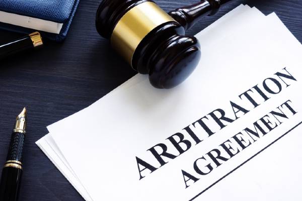 A gavel sits on top of a document titled "Arbitration Agreement."
