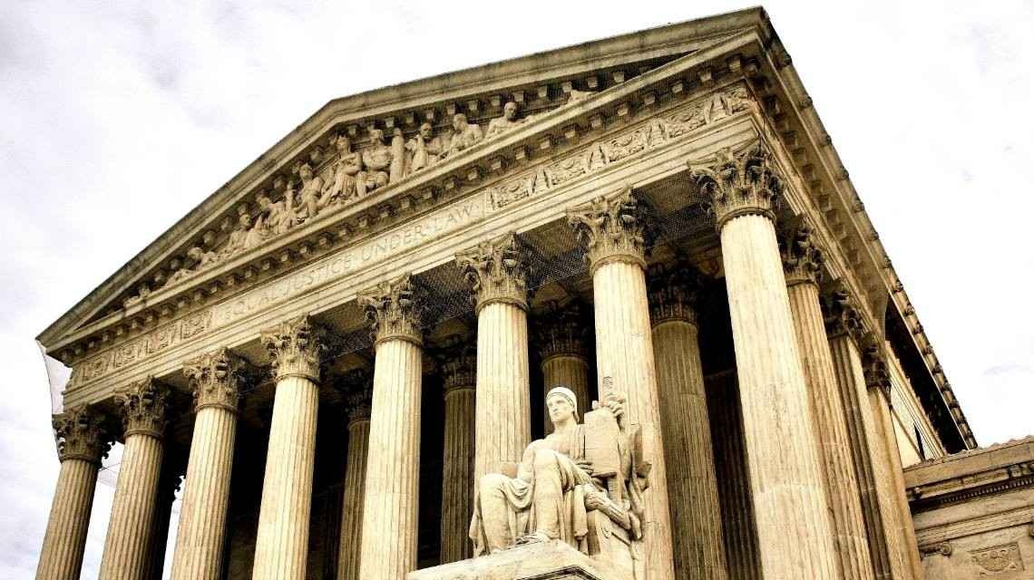 The U.S. Supreme Court building with a statue up front.