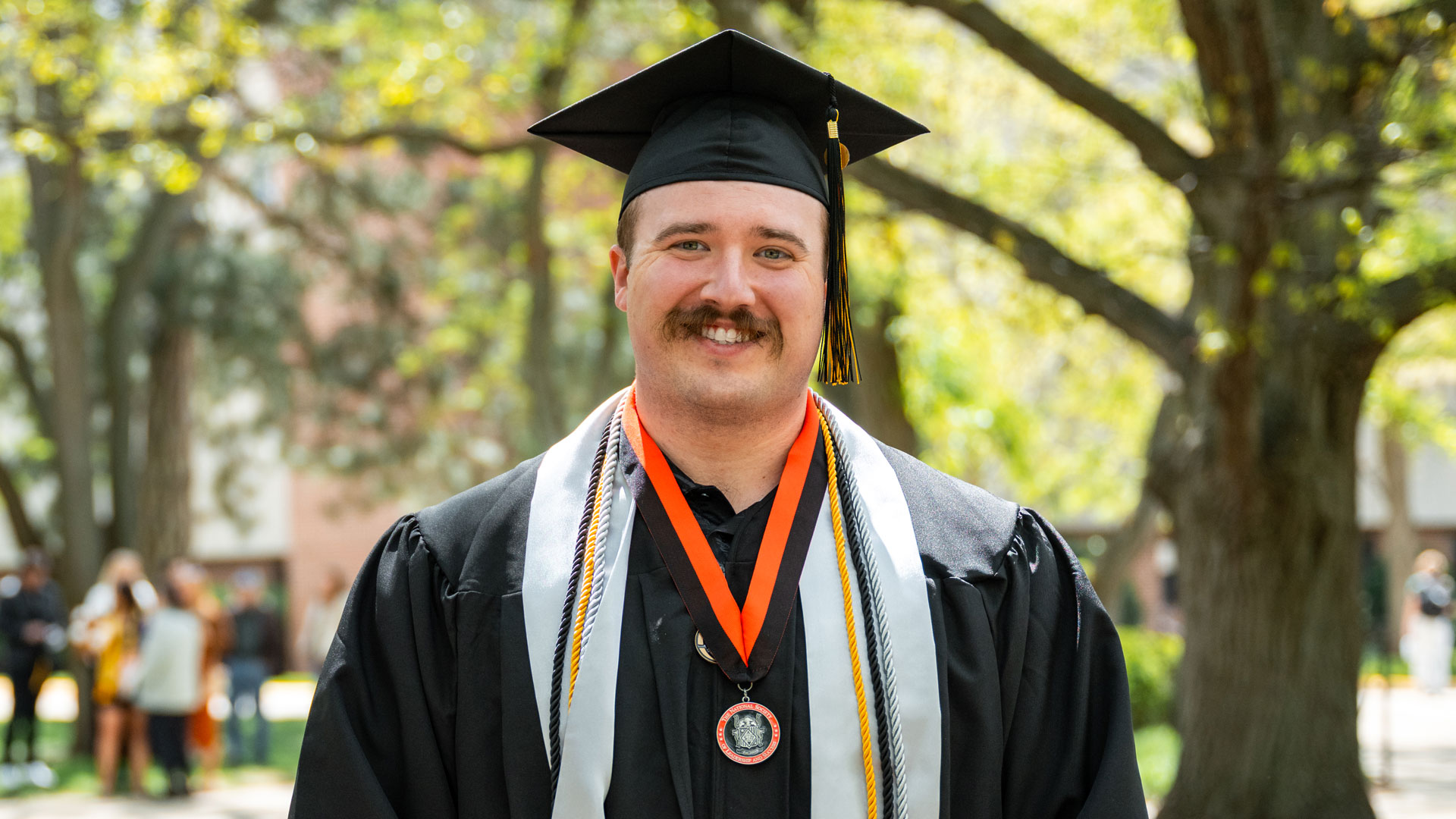 cap: Firefighter and paramedic Dillon Dunn is ready to move forward with his bachelor’s degree in fire science. (Purdue Global photo/Kelsey Lefever)
alt: Dillon Dunn stands outside in his cap and gown holding his diploma.